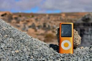 a laranja ipod sentado em topo do uma pilha do pedras foto