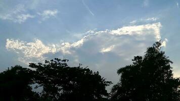 azul céu e branco nuvens acima a árvores em uma quente dia foto