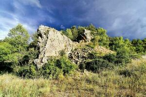 uma rochoso afloramento dentro a meio do uma campo foto