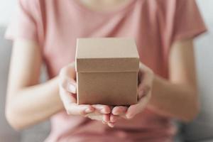 close-up de mãos de mulher segurando uma pequena caixa de presente. pequena caixa de presente nas mãos da mulher. foto