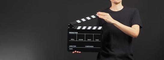 mão segurando claquete amarela e preta ou filme ardósia uso na produção de vídeo, cinema, indústria do cinema em fundo preto. foto