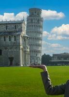 a inclinado torre do pisa em uma mulher mão dentro praça dei miraculos, toscana, Itália. foto