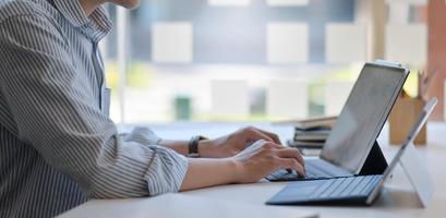 foto recortada de um homem usando um laptop e um tablet digital em um escritório moderno.