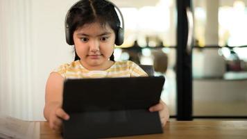 a garota está usando fones de ouvido, olhando atentamente para o tablet. foto