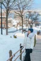 mulher turista visitando dentro hakodate, viajante dentro suéter passeios turísticos hachiman zaka declive com neve dentro inverno. ponto de referência e popular para atrações dentro Hokkaido, Japão. viagem e período de férias conceito foto