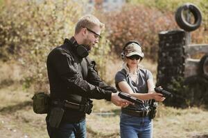 uma menina aprende para tiro uma pistola às uma tiroteio alcance com a instrutor foto