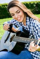 menina em uma verde Prado jogando guitarra foto