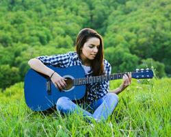 menina em uma verde Prado jogando guitarra foto