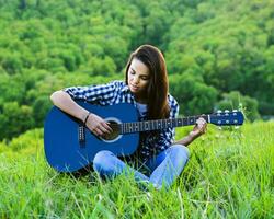 menina em uma verde Prado jogando guitarra foto