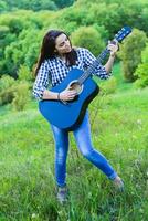 menina em uma verde Prado jogando guitarra foto