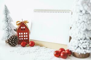 a branco calendário zombar acima para entrar texto de a festivo cena do lindo Natal árvore adornado, com Natal bolas, pinho cones, vermelho casa presente caixa amarrado dourado fita. conceito sobre importante dia. foto