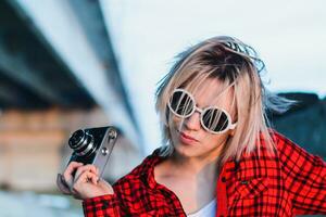 menina posando com uma Câmera debaixo a ponte foto