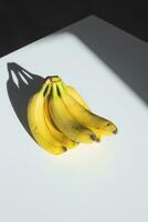 uma grupo do bananas em uma branco mesa dentro luz solar. foto