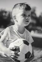 pequeno Garoto jogando com uma futebol bola em a campo dentro verão foto