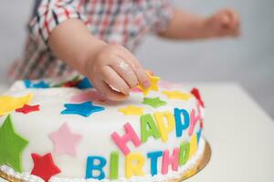 pequeno bebê toques dele aniversário bolo que mentiras em a mesa foto