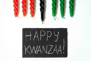 feliz conceito de kwanzaa. feriado afro-americano. letras de felicitações e sete velas - vermelho, preto e verde. símbolo da herança africana em fundo branco. foto