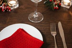 Natal mesa contexto. prato e talheres em vermelho guardanapo. preparando para festivo jantar. velas queimando em mesa em Natal véspera. foto