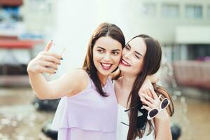 dois lindo irmãs Faz selfie em a rua foto