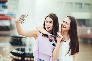 dois lindo irmãs Faz selfie em a rua foto