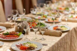 servido festivo mesa com lanches, copos, copos, talheres e guardanapos para uma banquete foto