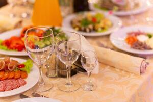 servido festivo mesa com lanches, copos, copos, talheres e guardanapos para uma banquete foto