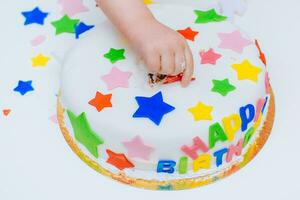 pequeno bebê toques dele aniversário bolo que mentiras em a mesa foto