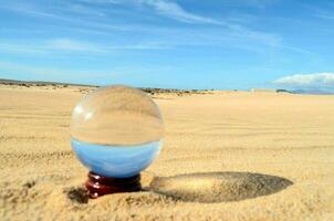 uma vidro bola dentro a areia foto