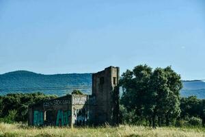 a velho abandonado construção dentro a meio do uma campo foto