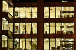 padronizar do escritório edifícios janelas iluminado às noite. vidro arquitetura , corporativo construção às noite - o negócio conceito. foto