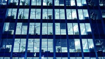 padronizar do escritório edifícios janelas iluminado às noite. vidro arquitetura , corporativo construção às noite - o negócio conceito. azul gráfico filtro. foto
