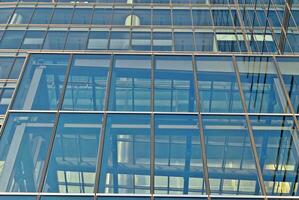 estrutural vidro parede refletindo azul céu. abstrato moderno arquitetura fragmento foto