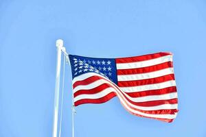 a americano bandeira vôo dentro a vento contra uma azul céu foto