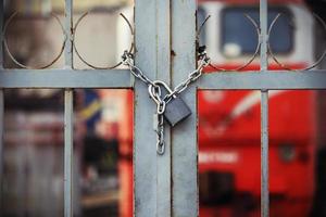 cadeado trancado pendurado em corrente no portão fechado da ferrovia foto