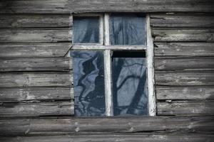 janela de madeira com moldura branca e vidros quebrados sujos foto