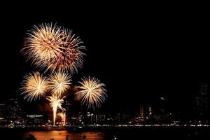 muitos fogos de artifício piscando com fundo de paisagem urbana à noite celebram o ano novo. foto