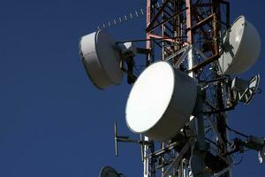 telecomunicação antena com múltiplo satélite contra a azul céu foto