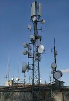 telecomunicação antena com múltiplo satélite contra a azul céu foto