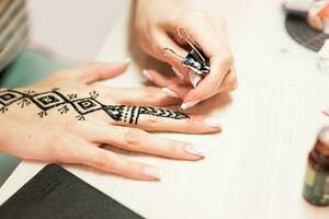 artista aplicando hena tatuagem em mulheres mãos. mehndi é tradicional indiano decorativo arte. fechar-se foto