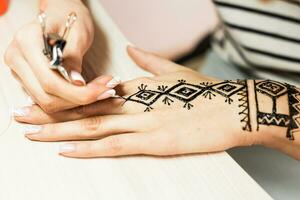 jovem mulher mehendi artista pintura hena em a mão foto