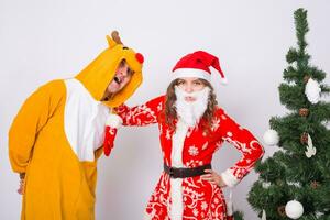 feliz jovem mulher dentro santa claus chapéu e homem dentro carnaval traje do cervo. diversão, feriado, Piada e Natal conceito foto