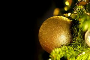 bolas de natal douradas closeup decoradas no pinheiro na noite de natal em fundo preto. foto