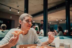 uma mulher comendo pizza dentro a escritório foto