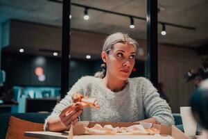 uma mulher comendo pizza dentro a escritório foto