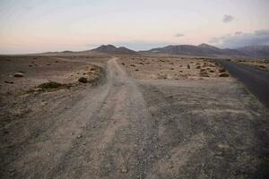 uma sujeira estrada dentro a meio do uma deserto com montanhas dentro a fundo foto