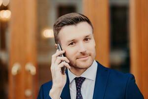 profissional homem dentro azul terno em telefone, confiante olhar, de madeira portas foto