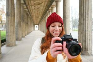 sorridente turista fotógrafo, leva cenário durante dela viagem, detém profissional Câmera e faz fotos