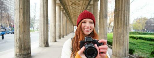 sorridente turista fotógrafo, leva cenário durante dela viagem, detém profissional Câmera e faz fotos