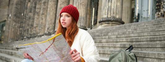 lindo jovem mulher, viajante com mochila detém papel mapa, explora cidade passeio turístico, planos rota para turismo popular atrações foto