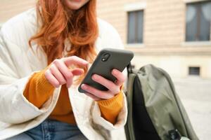 fechar acima do fêmea mãos digitando em Móvel telefone, usando Smartphone aplicativo. menina com Telefone tipos, senta ao ar livre e usa mapa foto