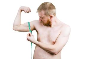 homem barbudo frustrado medindo seus bíceps foto